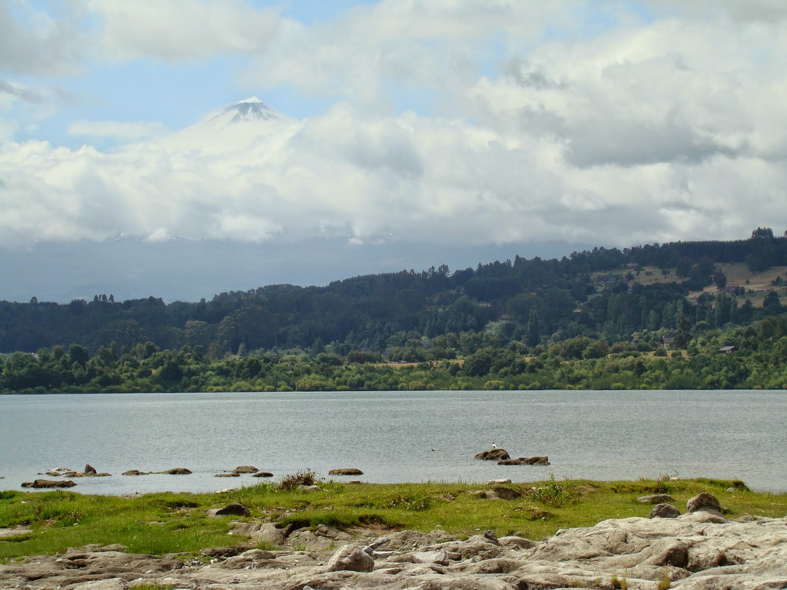 Lago e a pontinha do Vulcão Villarrica, escondido atrás das nuvens.